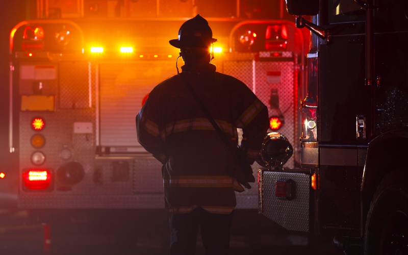 Fireman facing firetruck with lights on at night