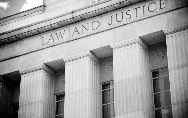 the words "law and justice" inscribed over a stately courthouse