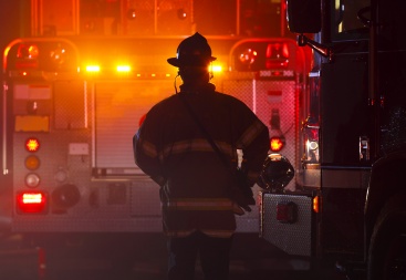 Fireman facing firetruck with lights on at night