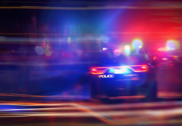 Police car speeding with lights on in response to a 911 emergency call, symbolizing law enforcement action, collision scenes, and accident-related investigations.