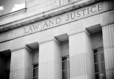 the words "law and justice" inscribed over a stately courthouse